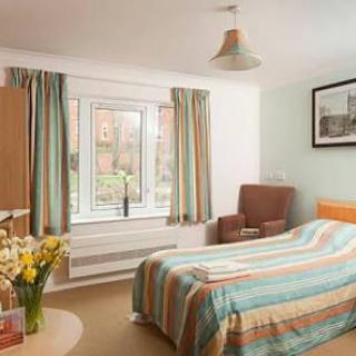 A cozy bedroom with a striped bedspread and matching curtains, featuring a large window and comfortable seating.