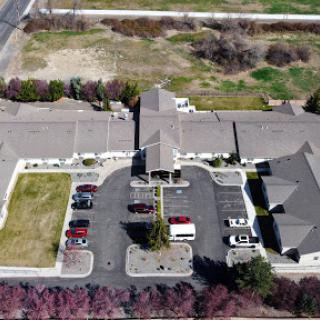 Aerial view of a building with a parking lot and surrounding landscape.