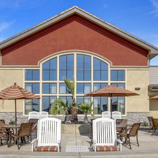 A building with large windows features an outdoor patio area with seating and umbrellas.