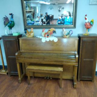 A beautifully arranged wooden piano with decorative accents and a mirror reflecting the surrounding interior.