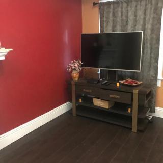 A cozy living room corner with a television on a stand against a red accent wall.