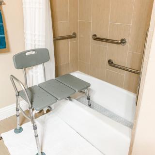 An accessible bathroom setup featuring a shower chair and grab bars for safety.