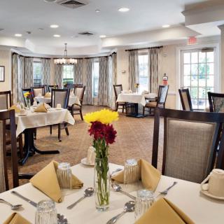 Elegantly set dining room with neatly arranged tables and a floral centerpiece.
