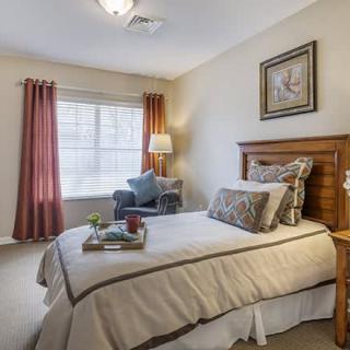 A cozy bedroom with a single bed and wooden furniture, featuring soft lighting and elegant decor.