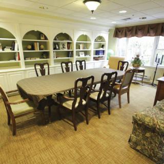 A well-lit conference room with a long table surrounded by chairs, and built-in bookshelves in the background.