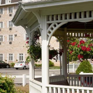A charming gazebo adorned with hanging flowers, set against a backdrop of a large building.
