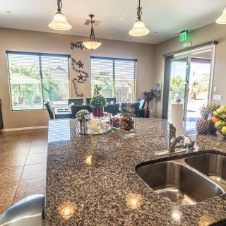A modern kitchen with a granite island overlooking a dining area.