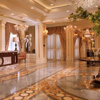 A luxurious hotel lobby with marble flooring and ornate chandeliers.