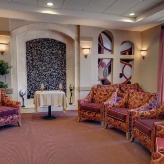 A cozy lounge area with upholstered chairs and a decorative stone wall feature.