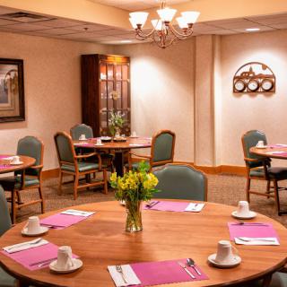 A well-arranged conference room with round tables, chairs, and a classic chandelier.