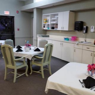 A cozy dining area with tables set, surrounded by a kitchenette.