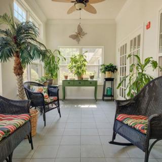 A bright sunroom with lush plants and comfortable wicker seating.
