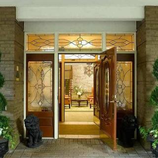 A welcoming entrance with decorative wooden doors and glass panels, flanked by potted plants.
