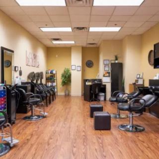 An interior view of a hair salon with chairs and mirrors lined up along the walls.