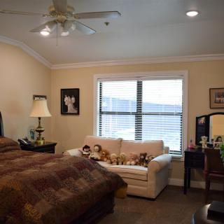 A cozy bedroom featuring a bed, sofa, and large window with natural light.