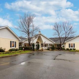 A residential building with a driveway and cloudy sky backdrop.