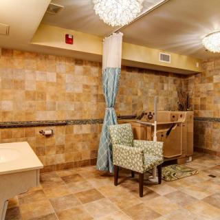 A well-lit interior room featuring tiled walls, a comfortable chair, and elegant light fixtures.