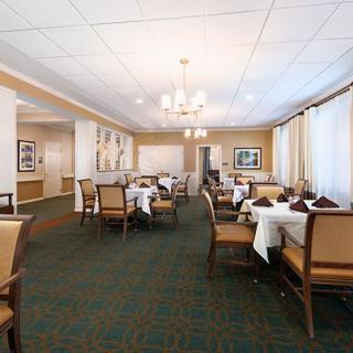 A spacious dining room with neatly arranged tables and chairs, featuring large windows and elegant chandeliers.