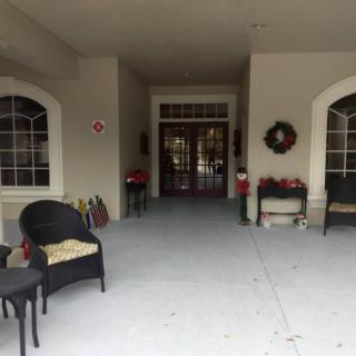 A welcoming porch entrance decorated with chairs, tables, and a wreath.