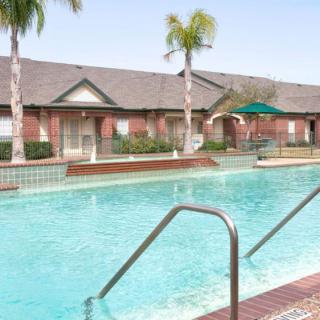 A swimming pool in a residential area surrounded by palm trees and buildings.