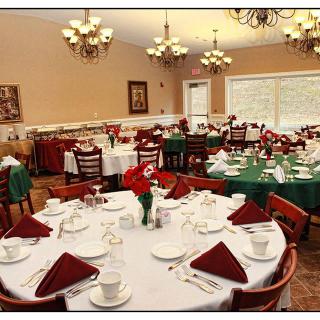 An elegant dining room set up with multiple tables, each adorned with white tablecloths and neatly arranged tableware.