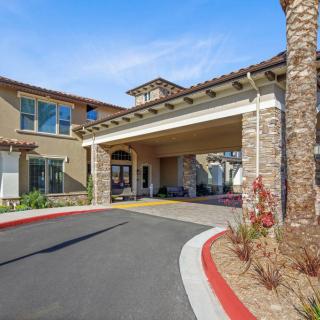 A modern building entrance with a covered driveway and stone walls.
