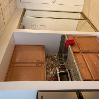 A compact kitchen space featuring wooden cabinets, a countertop with a sink, and an appliance set against a tiled backsplash.