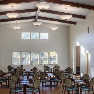 A bright dining area with multiple tables and chairs arranged neatly under ceiling lights.