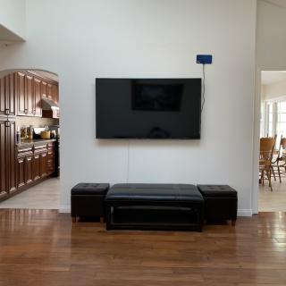 A modern living room with a mounted television, leather seating, and adjoining kitchen area.