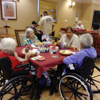 A group of elderly residents enjoying a meal together in a care facility.