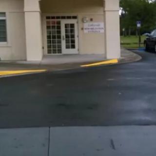 An entrance to a building with an adjacent driveway and parking lot.