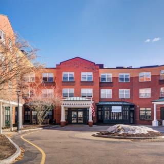A modern brick building with multiple windows and a prominent entrance under a clear blue sky.