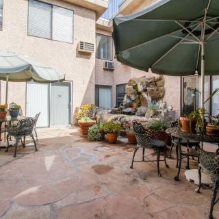 A charming courtyard patio with tables, chairs, umbrellas, and an abundance of potted plants.