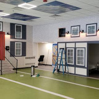 A spacious interior undergoing renovation, featuring mock windows and a ladder in the middle of the room.