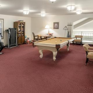 A spacious game room with a pool table and seating area.