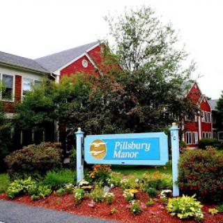 A red building with a 'Pleasant Bay Manor' sign surrounded by landscaped greenery.