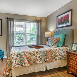 A cozy, well-decorated bedroom featuring a colorful bedspread and large window.