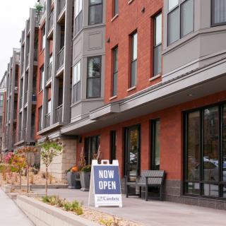 A newly opened commercial building with modern architecture along an urban sidewalk.