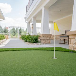 A well-maintained putting green with a yellow flag, set in a spacious outdoor area.
