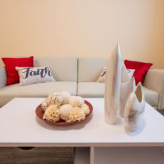 A cozy living room with a beige sofa, red and white cushions, and modern decorative items on the coffee table.