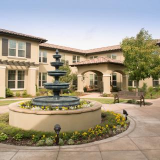 A beautifully landscaped courtyard with a central fountain and surrounding greenery.