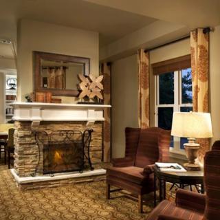 A cozy living room with a stone fireplace, armchairs, and warm lighting.