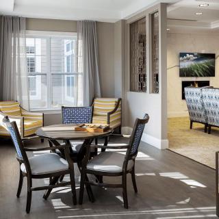 A cozy living area with a table and chairs near a large window.