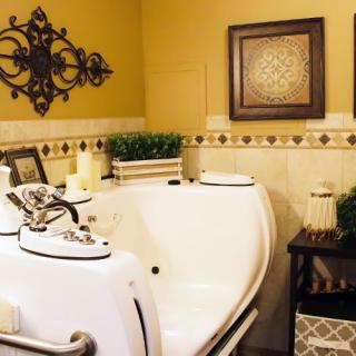 A cozy bathroom with a spa tub, warm yellow walls, and decorative wall art.