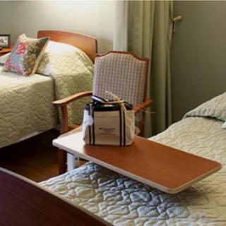 A cozy hospital room with two beds, a chair, and a small table.