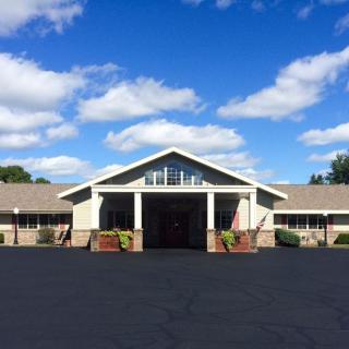 A wide-angle view of a building with a clear blue sky and scattered clouds.