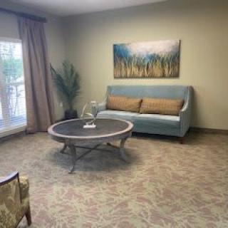 A cozy living room with a sofa, coffee table, and artwork on the wall.