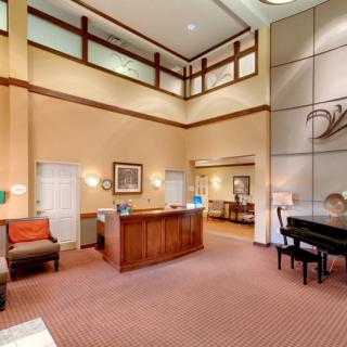 A hotel lobby with a reception desk, seating area, and grand piano.