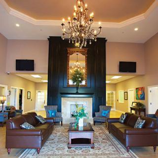 A luxurious lobby featuring a central chandelier, comfortable sofas, and an elegant fireplace.
