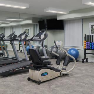 A modern gym with various exercise equipment including treadmills, a stationary bike, and weights.